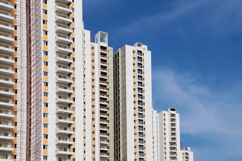Modern high-rise residential buildings with white facades and blue sky backdrop showcasing urban architecture.